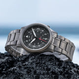 This Berny watch is elegantly displayed on a rocky surface with a background of the sea. It features a titanium bracelet and a black dial with both 12-hour and 24-hour markers. The watch combines durability and style, making it suitable for adventurous settings.